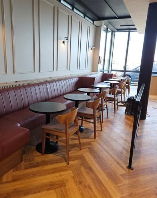 A long banquette with wall lights and small tables