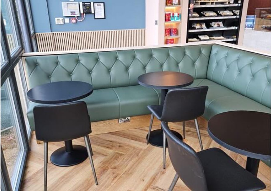 Cafe seating with green banquettes by a window